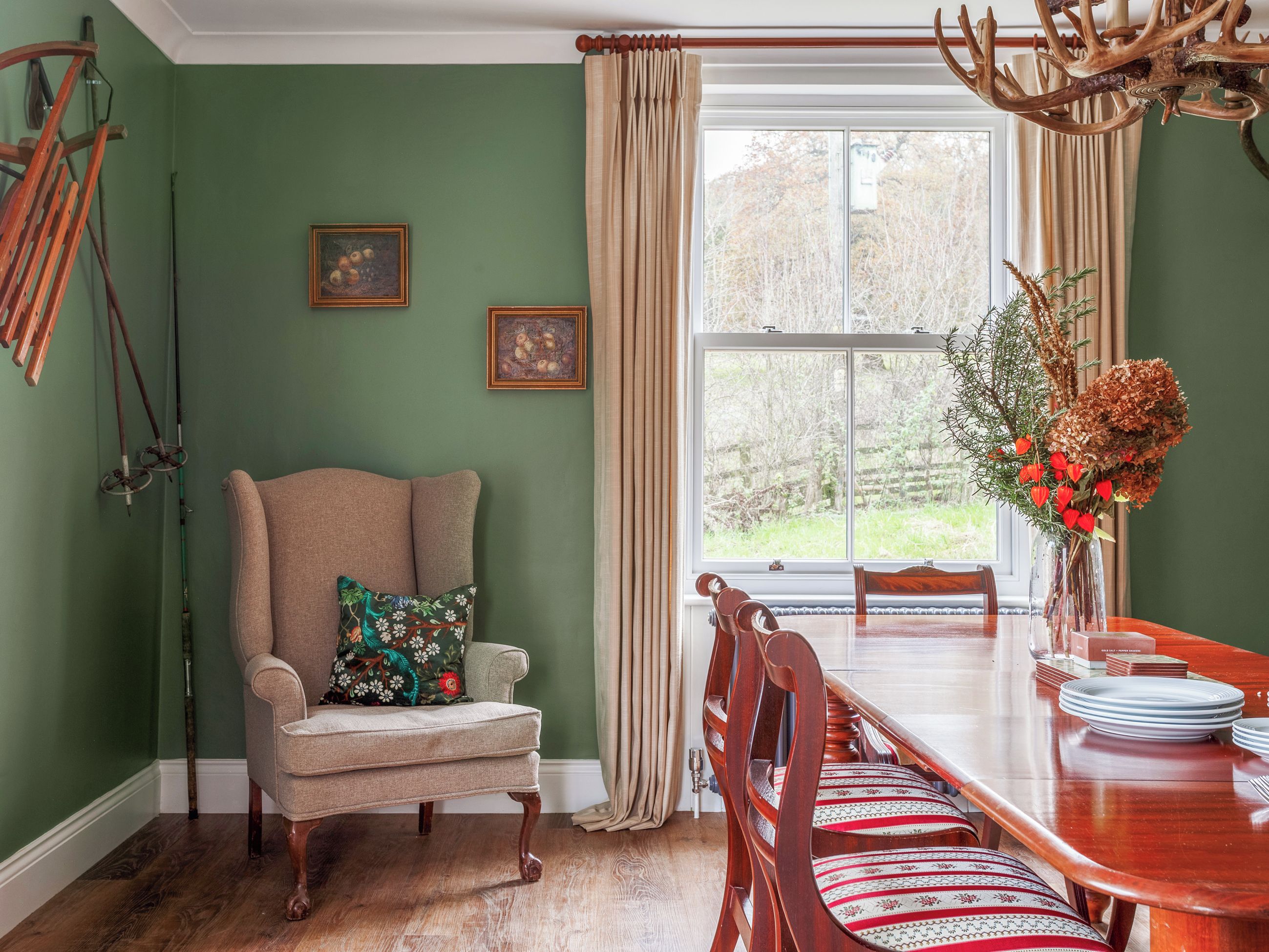 A dining area with a wooden table, chairs, and a window with curtains.