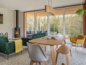 A modern living room with a large window, a fireplace, and a dining area. - Woodside Lodge - UKC9988 (Harewood, near Leeds)