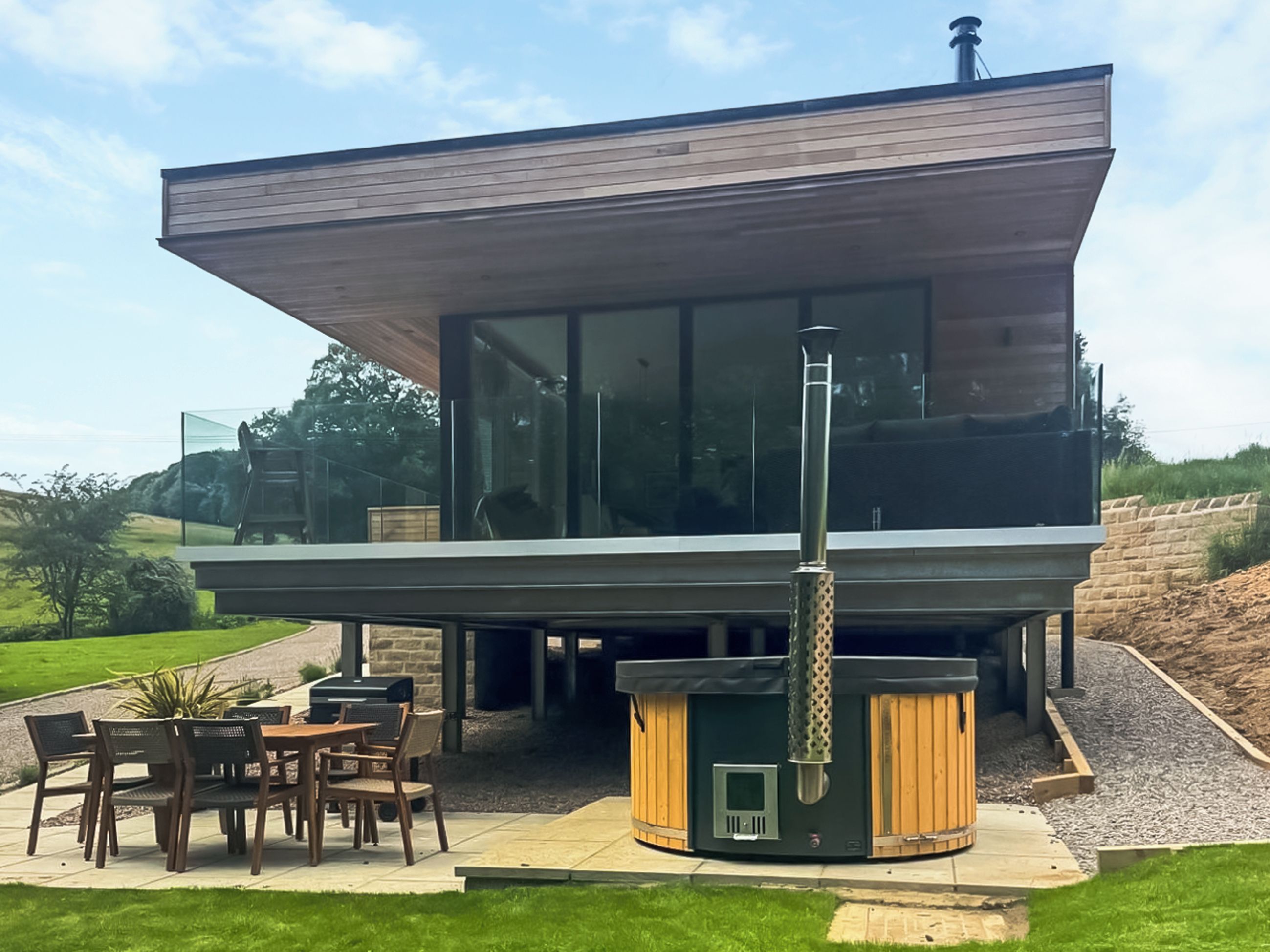 Un espace patio extérieur moderne, doté d’un barbecue intégré et de sièges.