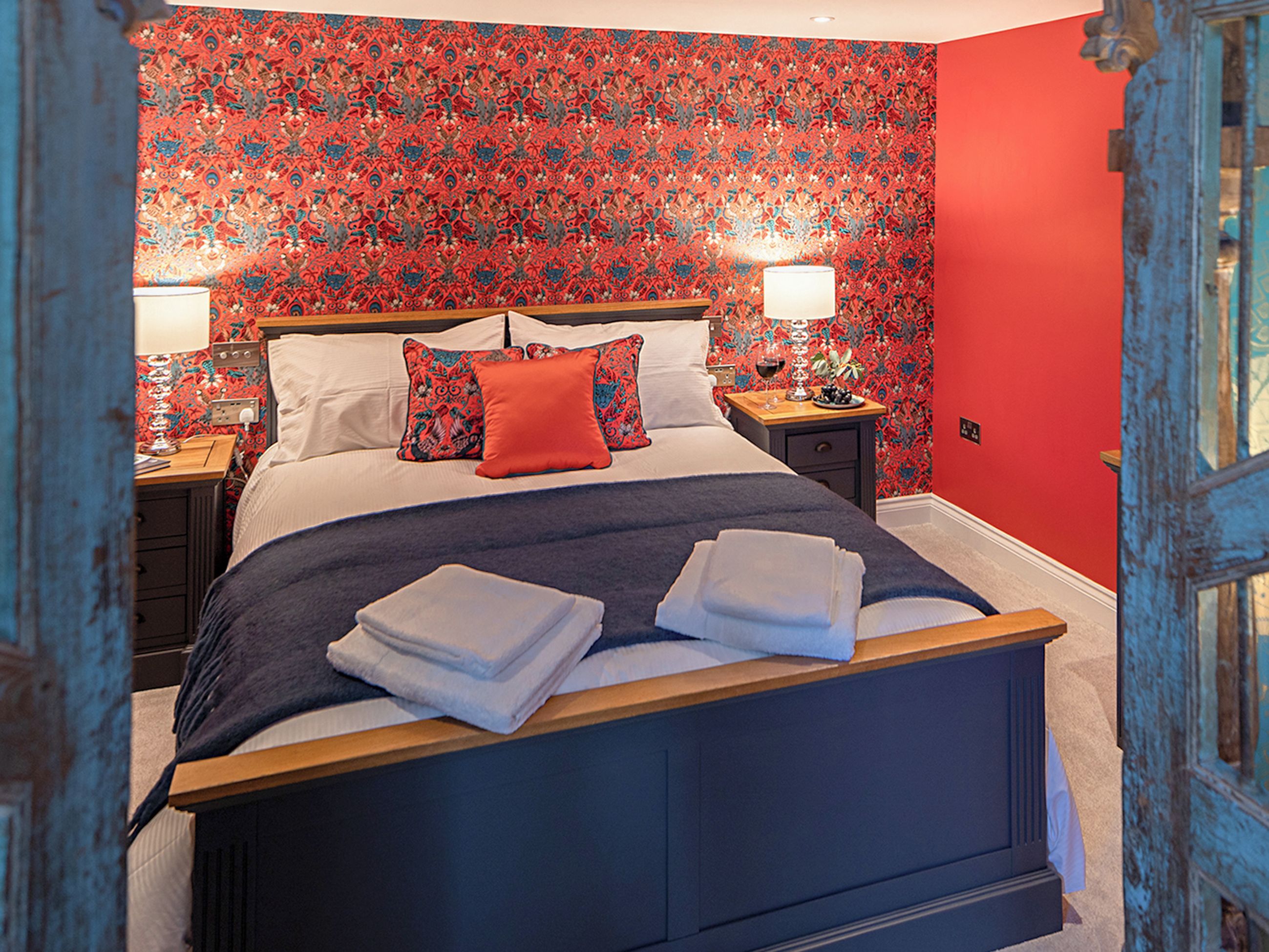 Une chambre à coucher avec un lit, deux tables de chevet, une commode et un papier peint à motifs.