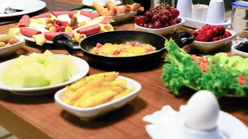 A breakfast buffet with various fruits, cheeses, and meats.