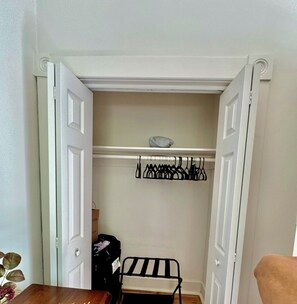 A closet with hanging clothes and a small bench. - 2-bedroom condo with a charming patio Savannah (Savannah)