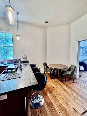 Eine moderne Küche mit Barbereich, Holzboden und einem Essbereich mit Stühlen und Tisch.
