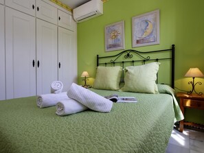 Un lit bien fait, avec des oreillers, une serviette enroulée et un magazine posés sur une couverture de lit verte à motifs matelassés.