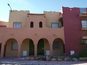 Un bâtiment doté de plusieurs arcades, d’un toit plat et d’une partie rouge sur le côté droit.