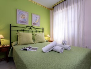 A neatly made bed with pillows, a folded towel, and a magazine on a green bedspread. - Sunstay Relax 48 Rio Marina Nerja (Nerja)