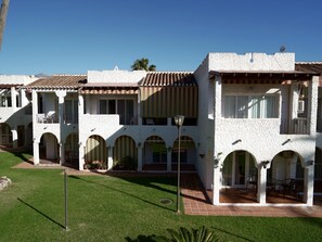 A white building with multiple balconies and arched windows, surrounded by a well-maintained lawn. - Sunstay Relax 48 Rio Marina Nerja (Nerja)