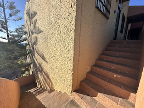 A staircase leading up to a building with a textured wall and a view of trees. - Sunstay Relax 48 Rio Marina Nerja (Nerja)