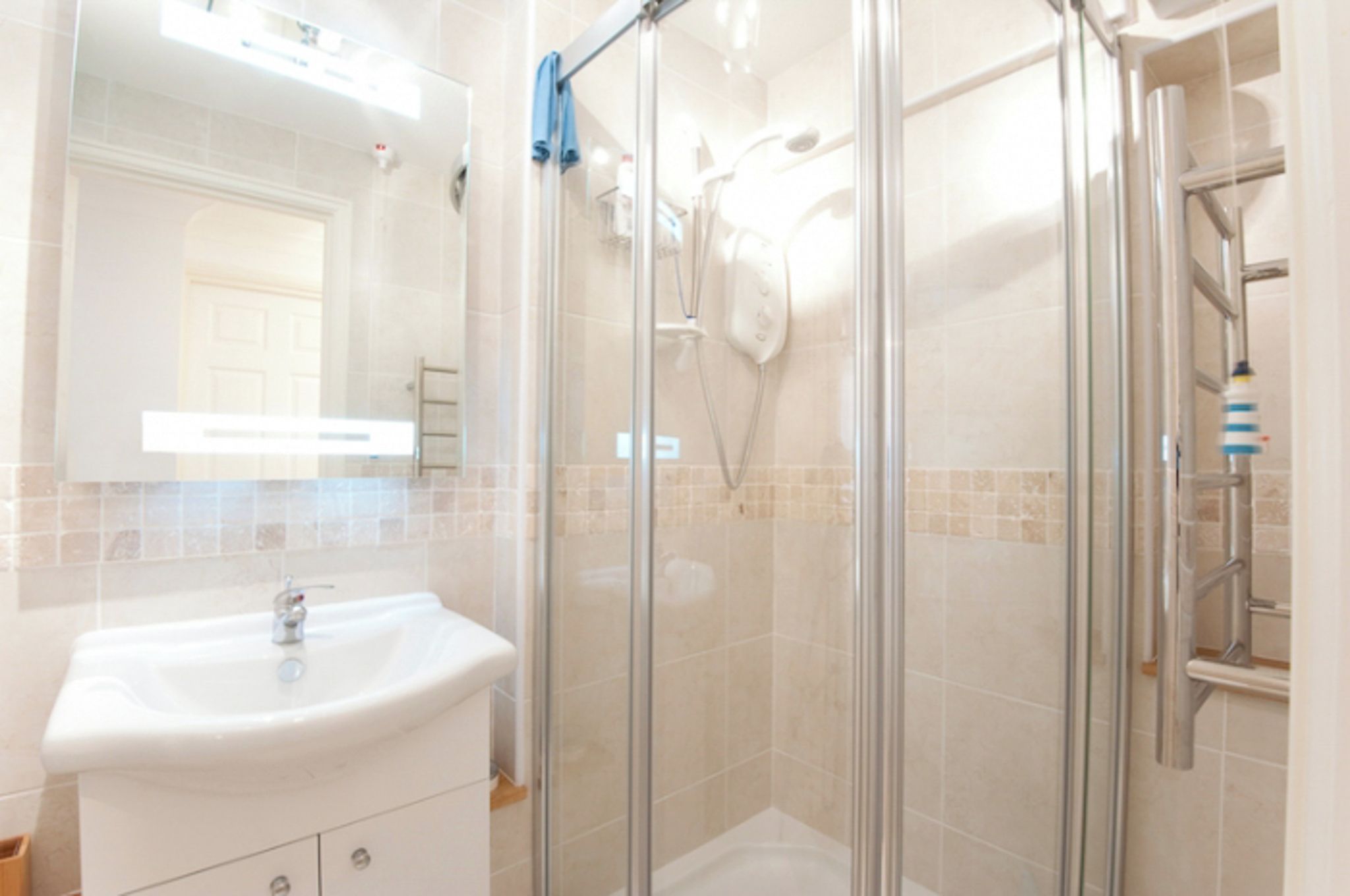 A bathroom with a glass-enclosed shower, a sink, and a mirror.