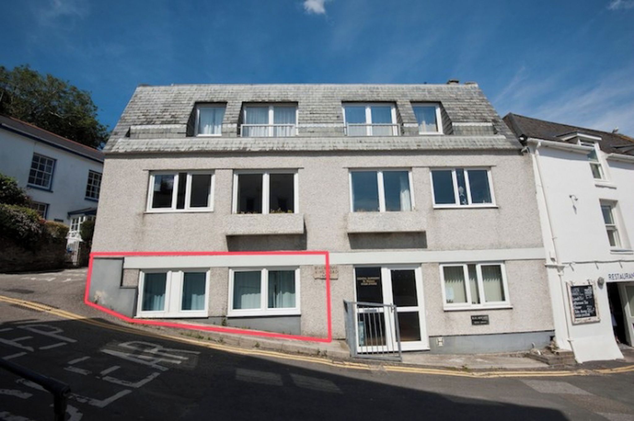 A two-story building with a flat roof, multiple windows, and a ground-level entrance.