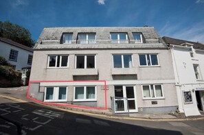 Un edificio de dos pisos con techo plano, varias ventanas y acceso a nivel de calle.