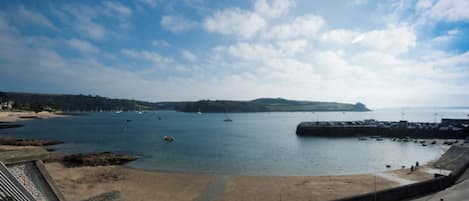 A coastal view with a sandy beach, a pier, and boats on the water.