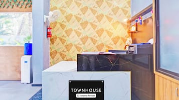 A reception desk with a 'TOWNHOUSE' sign, a fire extinguisher, a water dispenser, and a window with a view of greenery.
