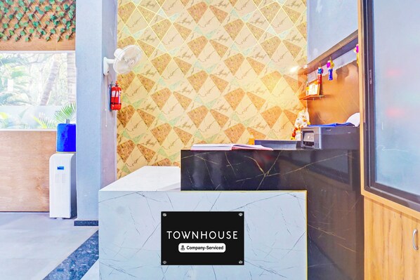 Un comptoir d’accueil avec une pancarte indiquant « TOWNHOUSE », un extincteur, un distributeur d’eau et une fenêtre donnant sur un espace verdoyant.