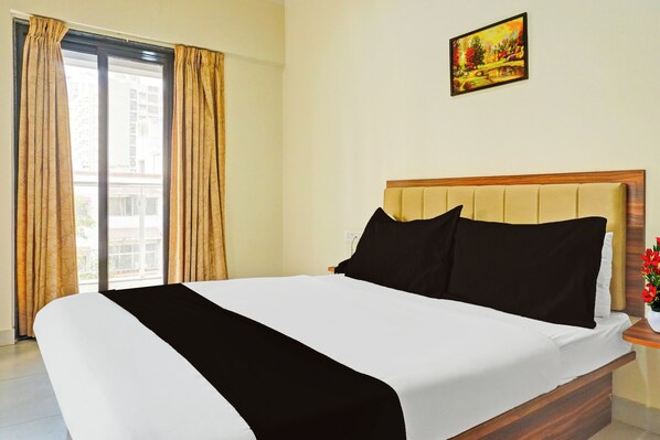 A hotel room with a bed, a painting on the wall, and a window with curtains.