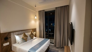 A hotel room with a bed, a TV, a window with curtains, and a ceiling fan. - Super Townhouse Hitech City Near Yashoda (Hyderabad)
