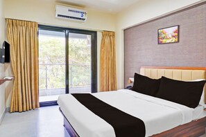 A hotel room with a bed, a flat-screen TV, a window with curtains, and a wall-mounted air conditioner. - Super Townhouse Hitech City Near Yashoda (Hyderabad)