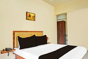 Une chambre d’hôtel avec un lit, une table de chevet avec un téléphone et un tableau au mur.