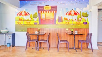 A cafe with outdoor seating, a wooden floor, and a mural on the wall.