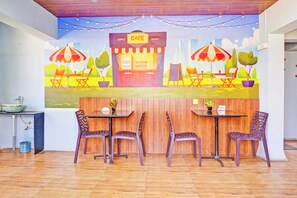 Café com mesas ao ar livre, piso de madeira e um mural na parede.