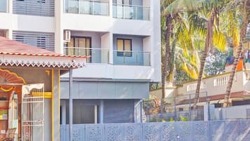 A multi-story building with balconies, a covered entrance with a decorative awning, and a metal fence with intricate cut-out patterns.