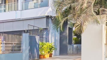 A modern building with a gated entrance, potted plants, and a palm tree.