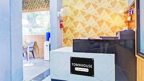 A reception area with a marble counter, a fire extinguisher, and a patterned wall. - Super Townhouse Hitech City Near Yashoda (Hyderabad)