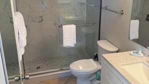 Een badkamer met een douchecabine, toilet en een wastafel met aanrechtblad.