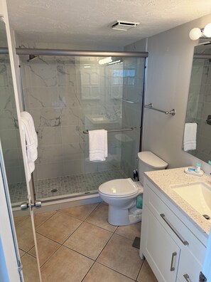 Une salle de bain avec une douche à parois de verre, des toilettes et un lavabo avec un plan de travail.