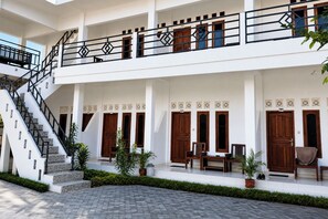 A multi-level building with a staircase, wooden doors, and a seating area with chairs and a table.