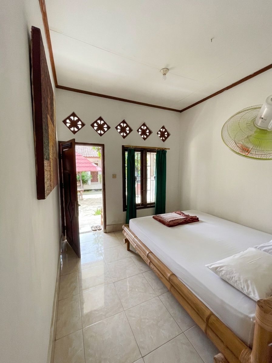 Quarto com cama, ventoinha e porta que dá para área externa.