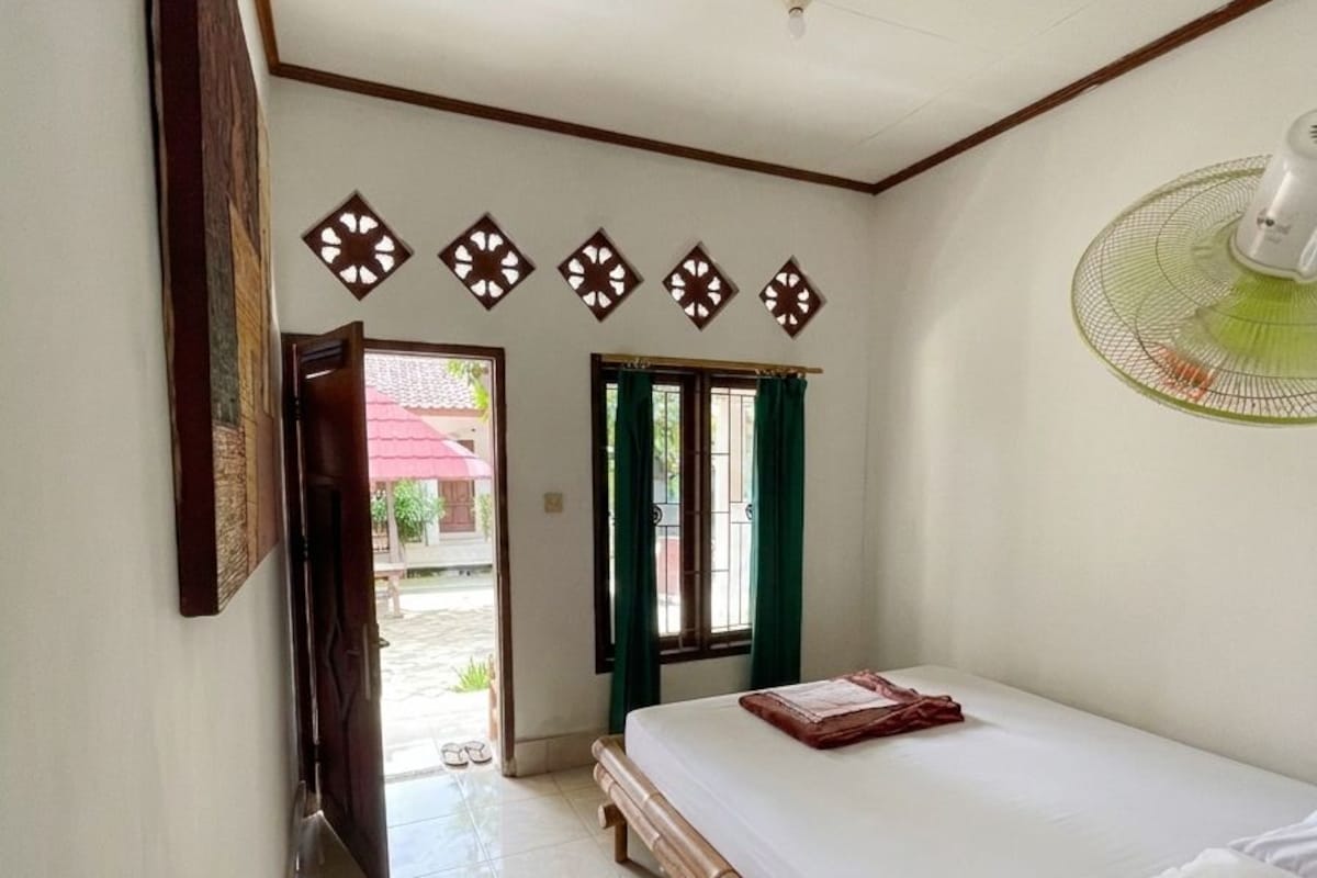 A room with a bed, a fan, and a door leading to an outdoor area.