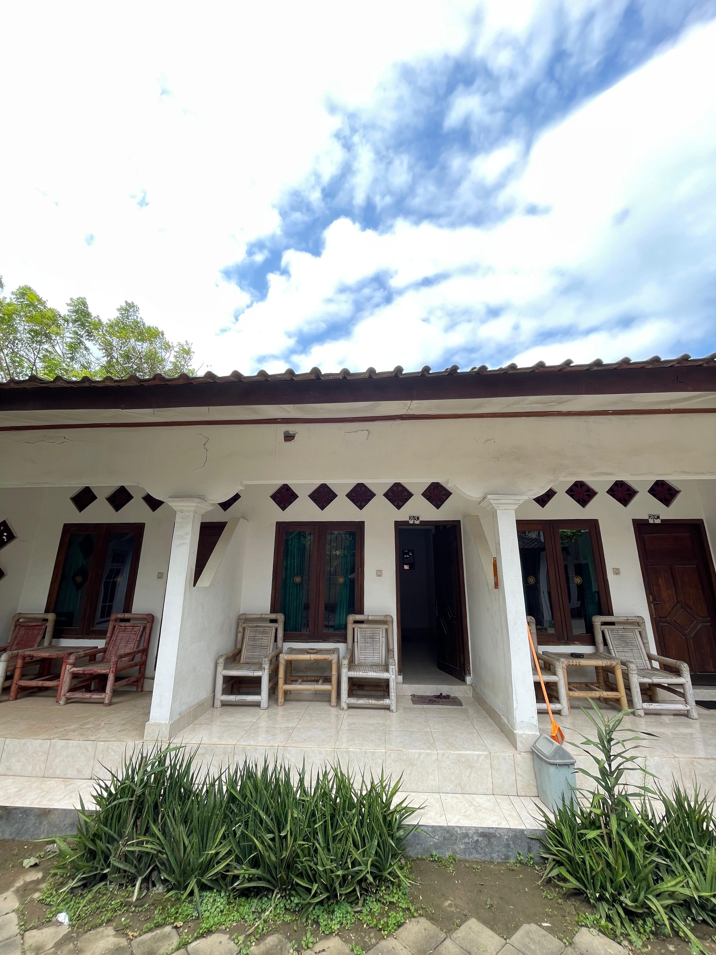 A building with a covered porch, multiple doors, and outdoor seating.