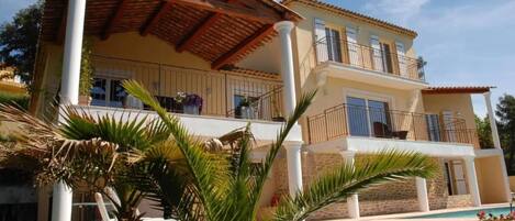 Un bâtiment à deux étages doté d’un balcon, d’une piscine et d’un jardin.