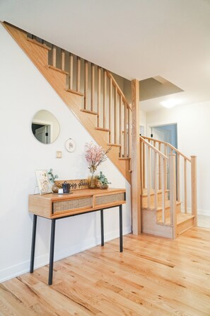 A staircase with wooden railings and a console table with decorative items. - Beautiful Muskoka Cottage with Games, BBQ & Views (Huntsville)