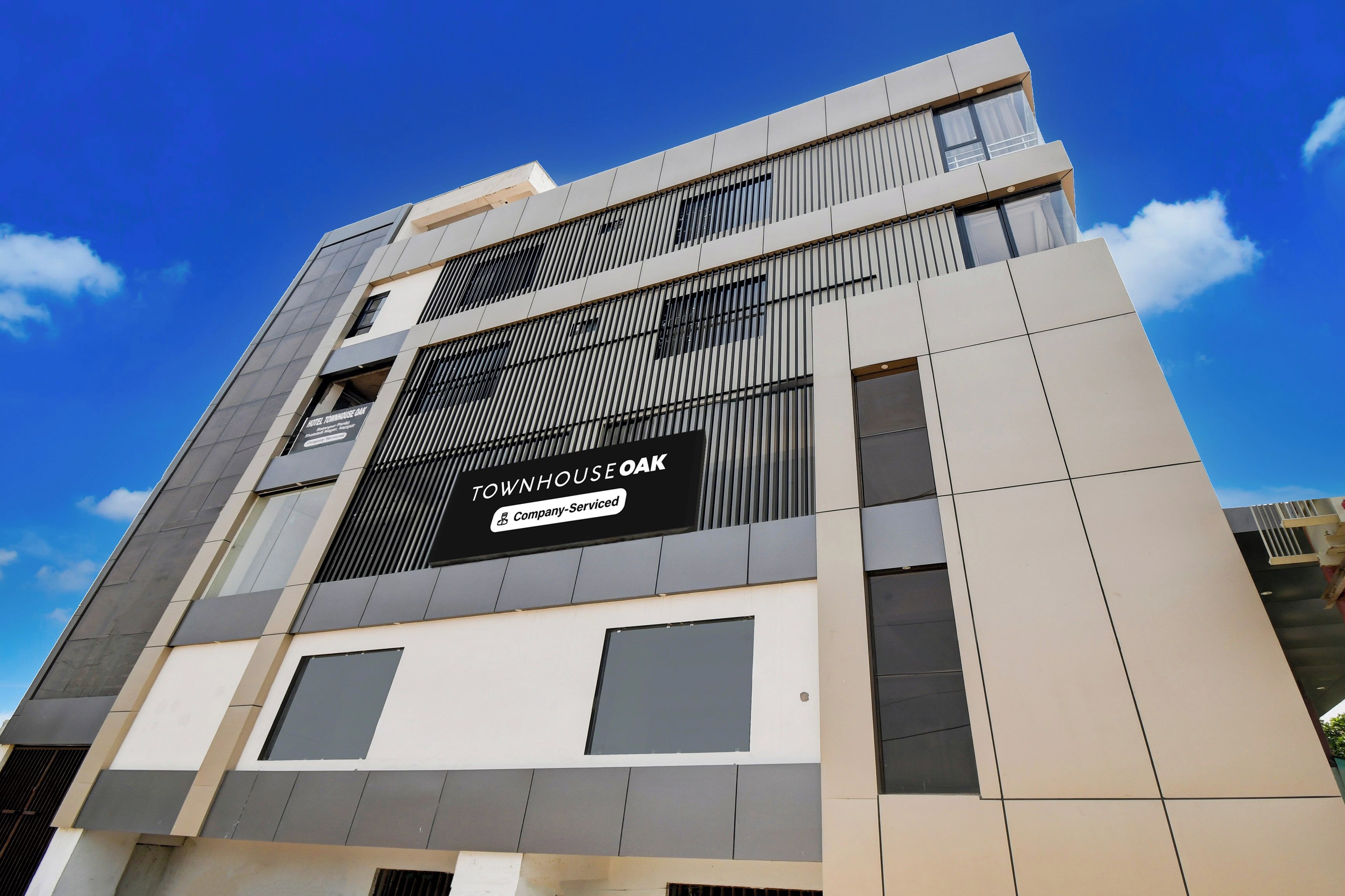 A modern building with a sign for 'TOWNHOUSE OAK' indicating it is a company-serviced property.