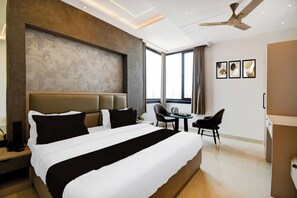 Una camera d'albergo con un letto grande, una scrivania, una sedia e una ventola a soffitto.