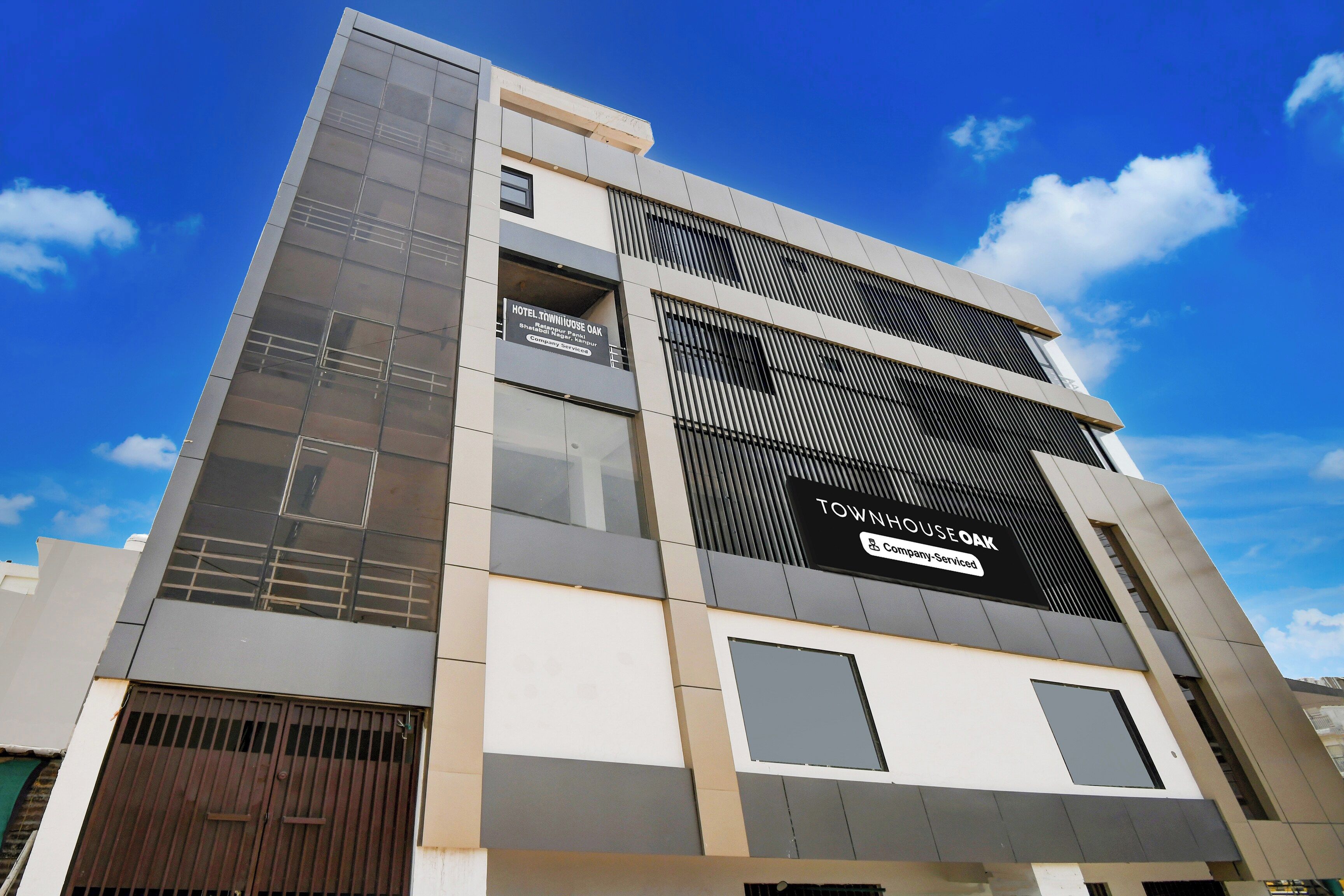 En moderne hotelbygning med tydelig skiltning for 'TOWNHOUSE OAK' og 'HOTEL TOWNHOUSE OAK'.