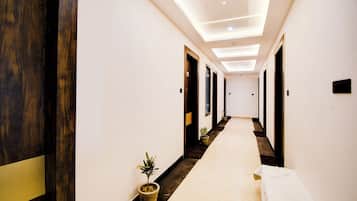 En hotellkorridor med modern design, med en lång passage, trädörrar och en krukväxt.
