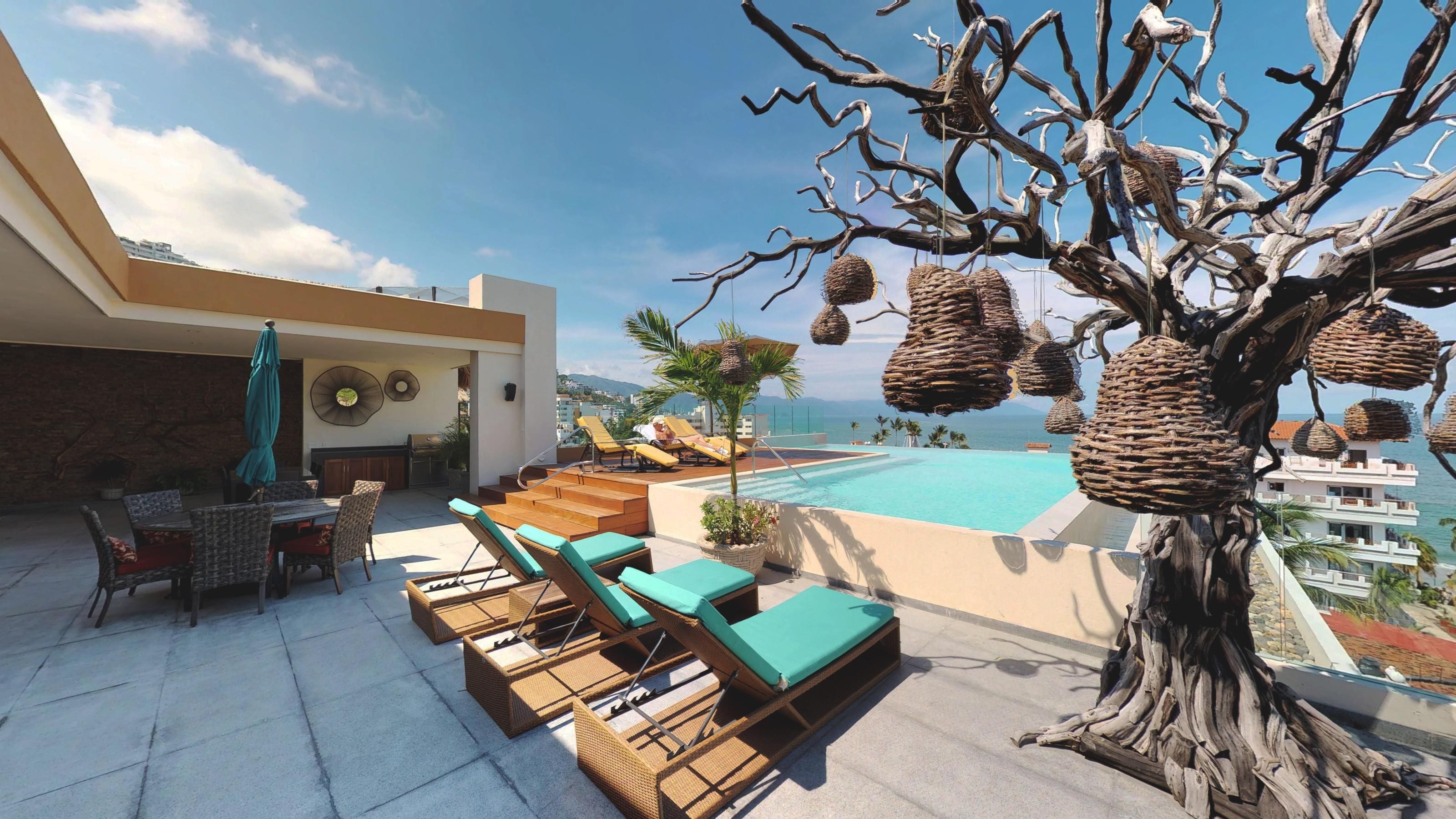 Un área de piscina en la azotea con sillones reclinables y una zona de comedor.