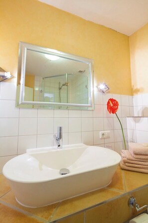 Ein Badezimmer mit einer weißen freistehenden Badewanne, einer Duschkabine aus Glas und einem Spiegel über dem Waschbecken.