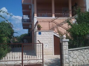 A multi-story residential building with a stone facade, a gated entrance, and a staircase leading to the upper floors. - Rooms Tatjana - Double Room (Supetar)