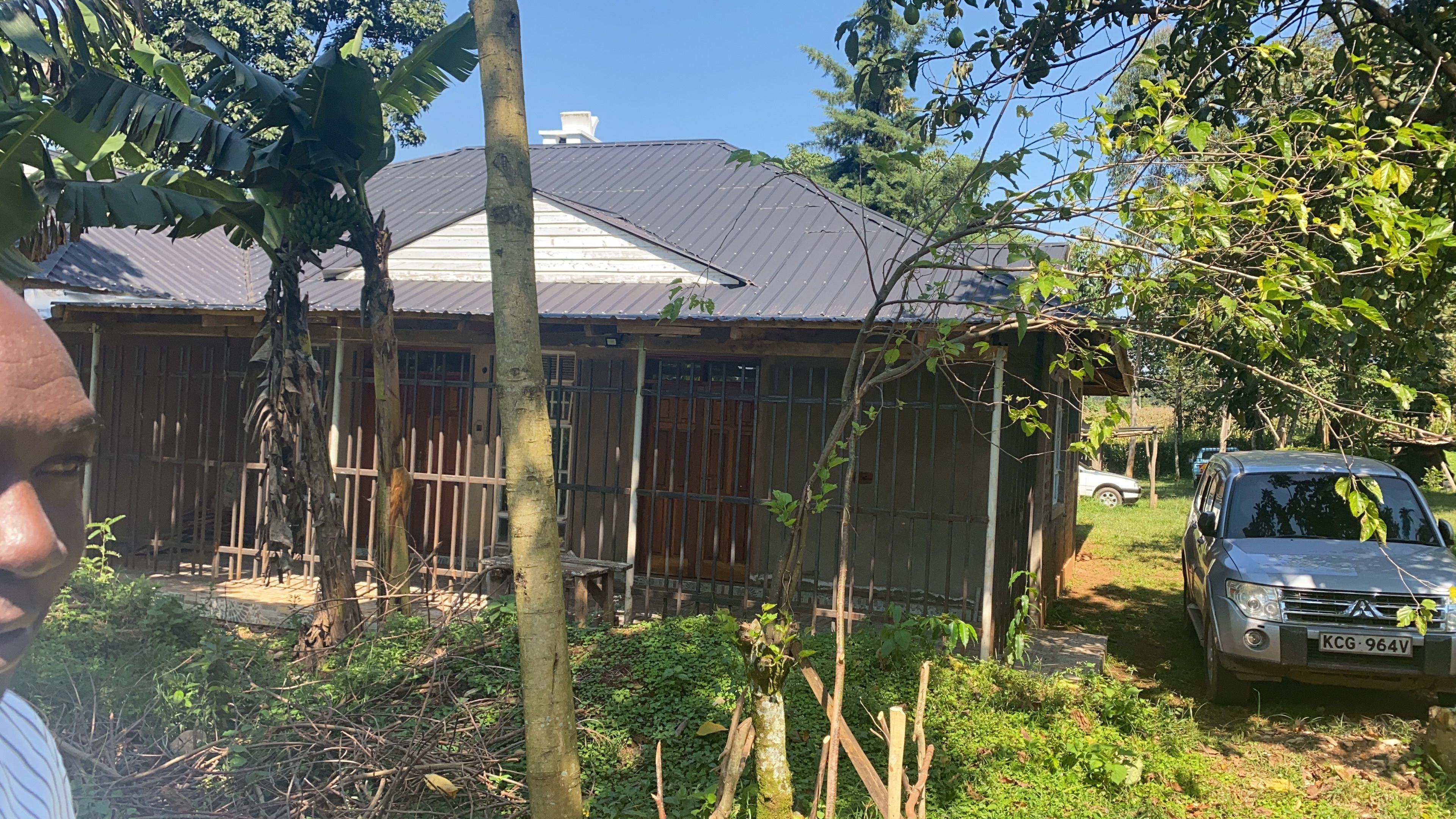 A residential property with a metal roof, a wooden fence, and a parked car.