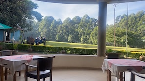 A covered outdoor seating area with tables and chairs, overlooking a well-maintained lawn and trees. - Serene 3-bedroom building in charming Kakamega County perfect for relaxing (Kakamega County)