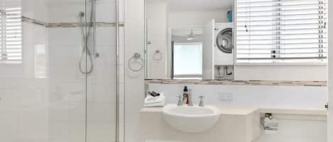 A modern bathroom with a glass shower enclosure, a sink with a mirror above it, and a toilet.