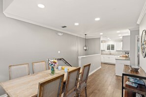 Eine moderne Küche mit weißen Schränken, einer Holz Arbeitsplatte und einem Essbereich mit einem Holztisch und Stühlen.