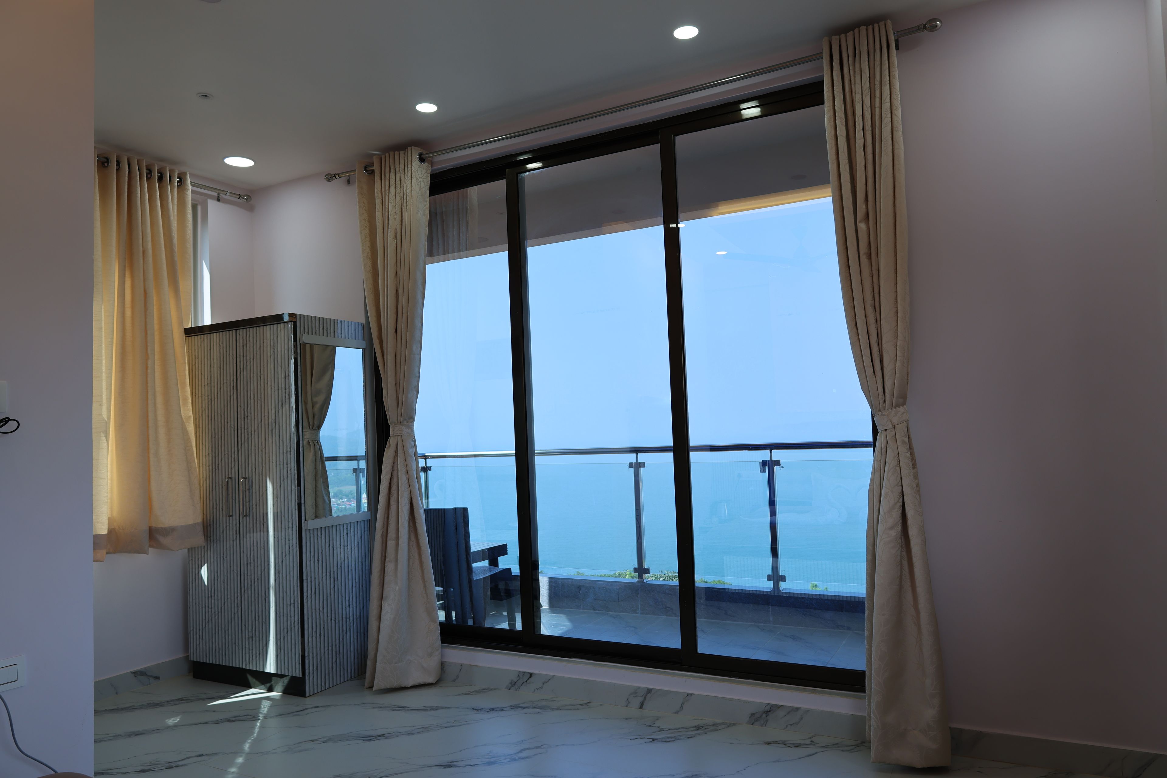 Una habitación con un gran ventanal corredera que da a un balcón con vistas al mar.