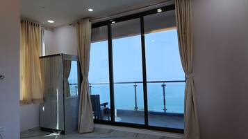 Una habitación con un gran ventanal corredera que da a un balcón con vistas al mar.
