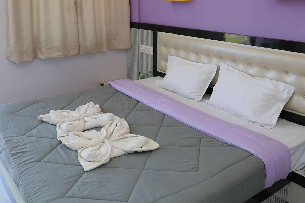 Habitación de hotel con cama, ventana con cortinas, equipo de aire acondicionado y pared con detalle amarillo.