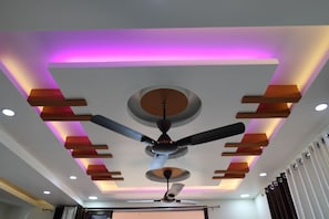 A ceiling with a central fan, recessed lighting, and a purple accent light.
